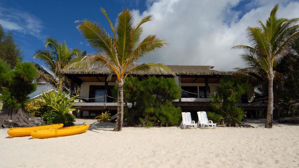 Rendezvous Villas في راروتونغا: منتجع على الشاطئ مع وجود اثنين من الزوارق الصفراء على الشاطئ