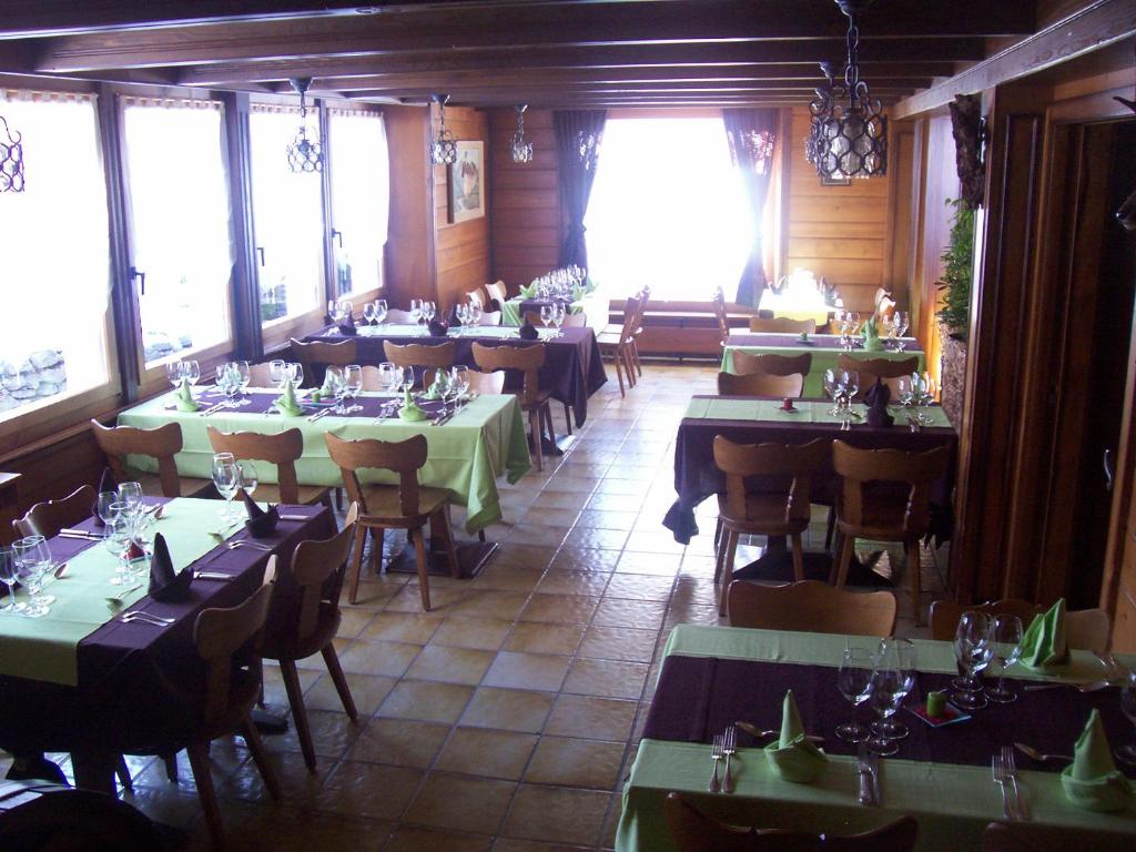jadalnia ze stołami, krzesłami i oknami w obiekcie Hôtel du Gd-St-Bernard w mieście Liddes