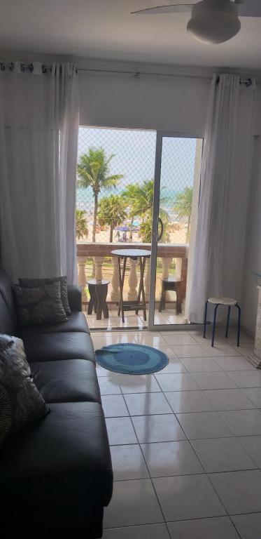 a living room with a couch and a view of the beach at Apto Ocian in Praia Grande