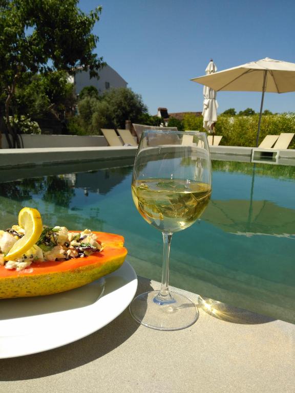 a glass of white wine next to a plate of food at Casas Do Contrabando in Marvão