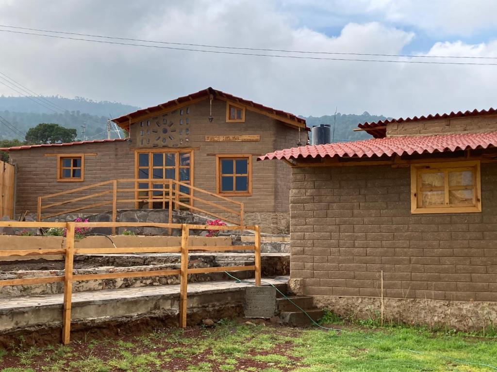 une maison en bois avec une clôture à côté d'un bâtiment dans l'établissement Hotel Finca Belén, à Tlaxco de Morelos