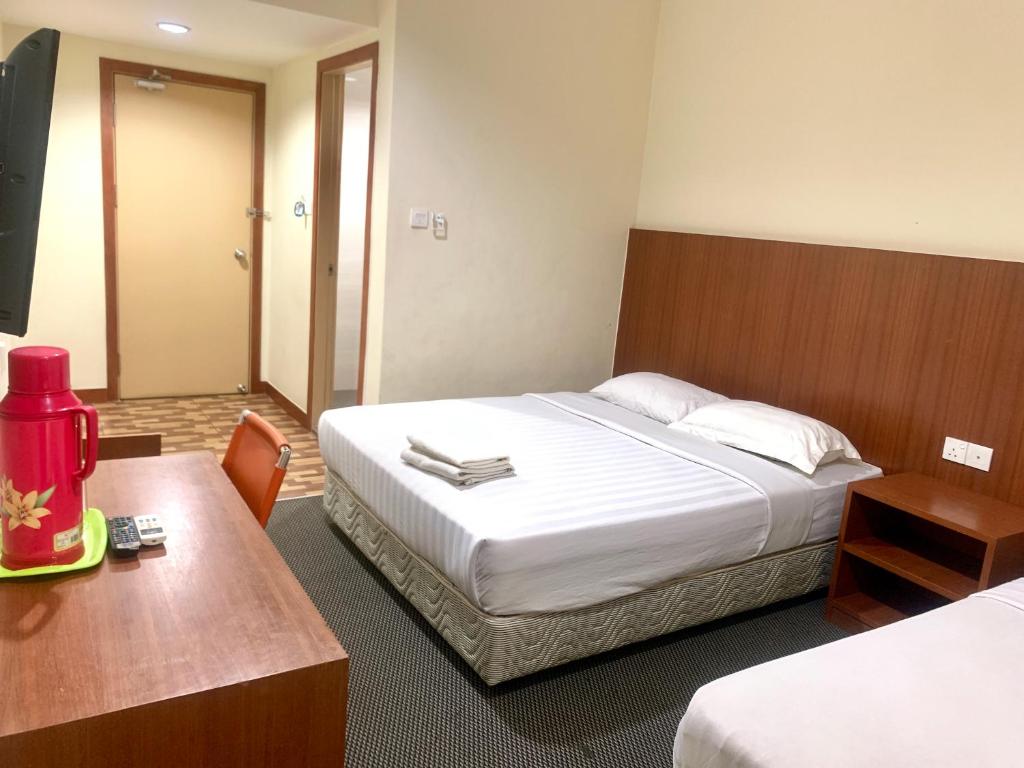 Cette chambre comprend un lit, une table et un bureau. dans l'établissement Grand Hotel 2, à Keningau