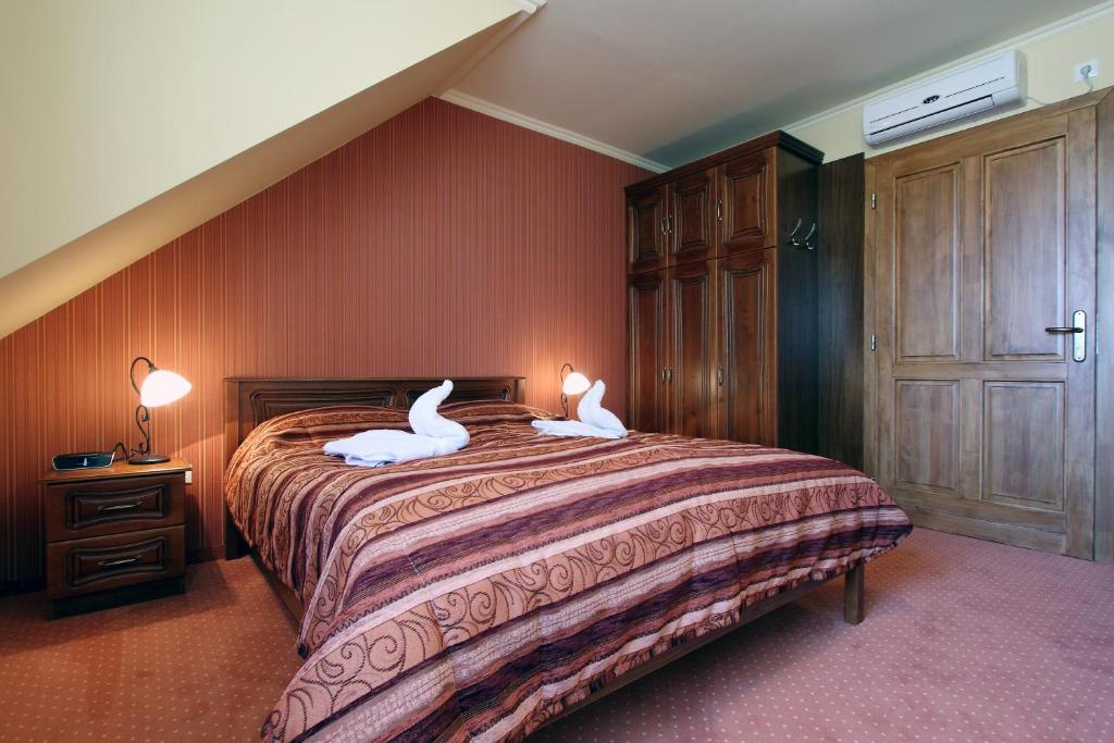 two swans are sitting on a bed in a bedroom at Family Panzio es Apartman Hazak in Lipót