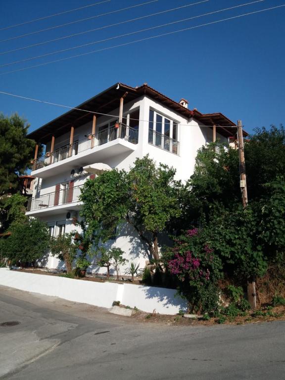 ein weißes Apartmenthaus mit einem Balkon und Bäumen in der Unterkunft Koukounari Studios in Neos Marmaras