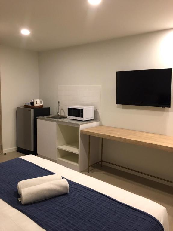 A bedroom wall combines a long desk with a television and a compact kitchenette.