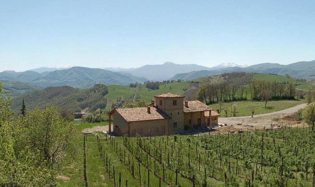 un antiguo edificio en un campo con montañas en el fondo en Agriturismo Il Filare, en Neviano degli Arduini