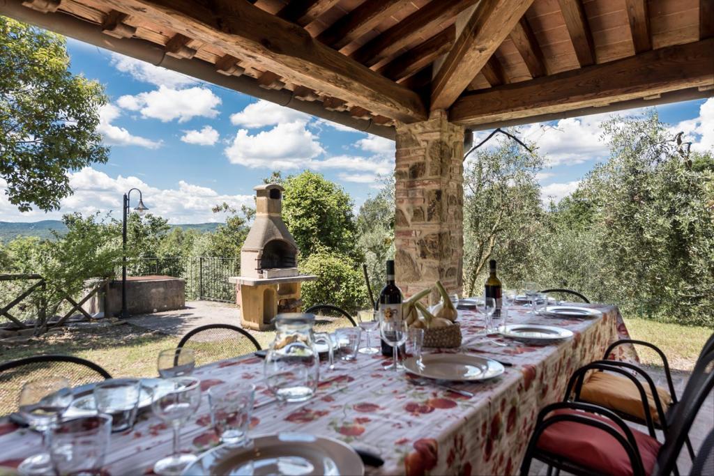 una mesa preparada para una comida bajo una pérgola en Villa Bellaria Lucignano, en Lucignano