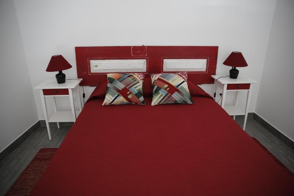 1 cama roja con 2 mesas y 2 lámparas en Casa da Praça en Ponte de Sor