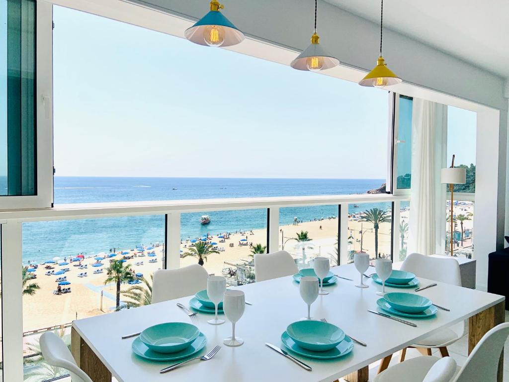 uma sala de jantar com uma mesa e vista para a praia em Seafront New Apartment Boutique em Lloret de Mar