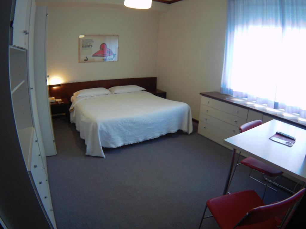 ein Hotelzimmer mit einem weißen Bett und einem Schreibtisch in der Unterkunft Albergo Residence Italia Vintage Hotel in Pordenone