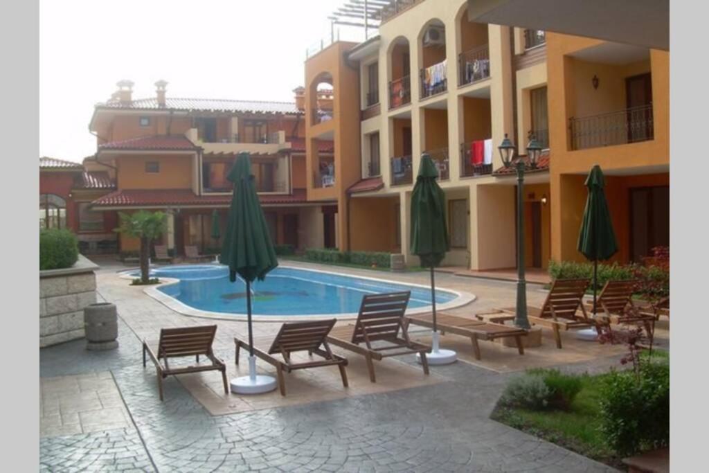 a courtyard with chairs and umbrellas and a swimming pool at Стyдия в комплексе Marinavill Sveti-Vlas in Sveti Vlas