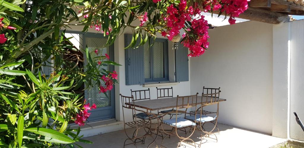 una mesa y sillas en un porche con flores rosas en Le Mas des Sagnes, en Saintes-Maries-de-la-Mer