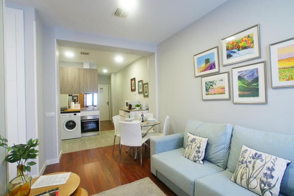 a living room with a blue couch and a kitchen at Apartamento al lado de Gran Via - Pink in Madrid