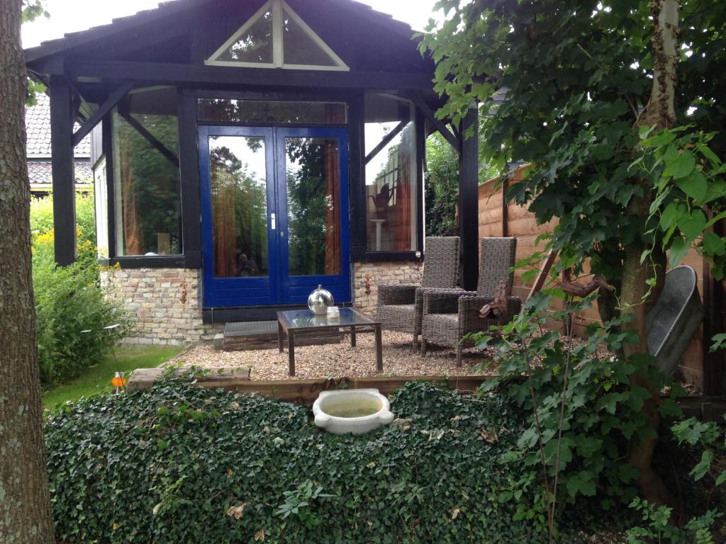 een tuinhuisje met een blauwe deur in een tuin bij Vrijstaand Koetshuis Marron in Barsingerhorn