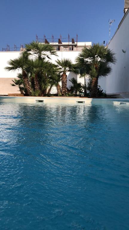 une piscine d'eau bordée de palmiers sur une plage dans l'établissement B&B RESORT SIGNORILE, à Bari