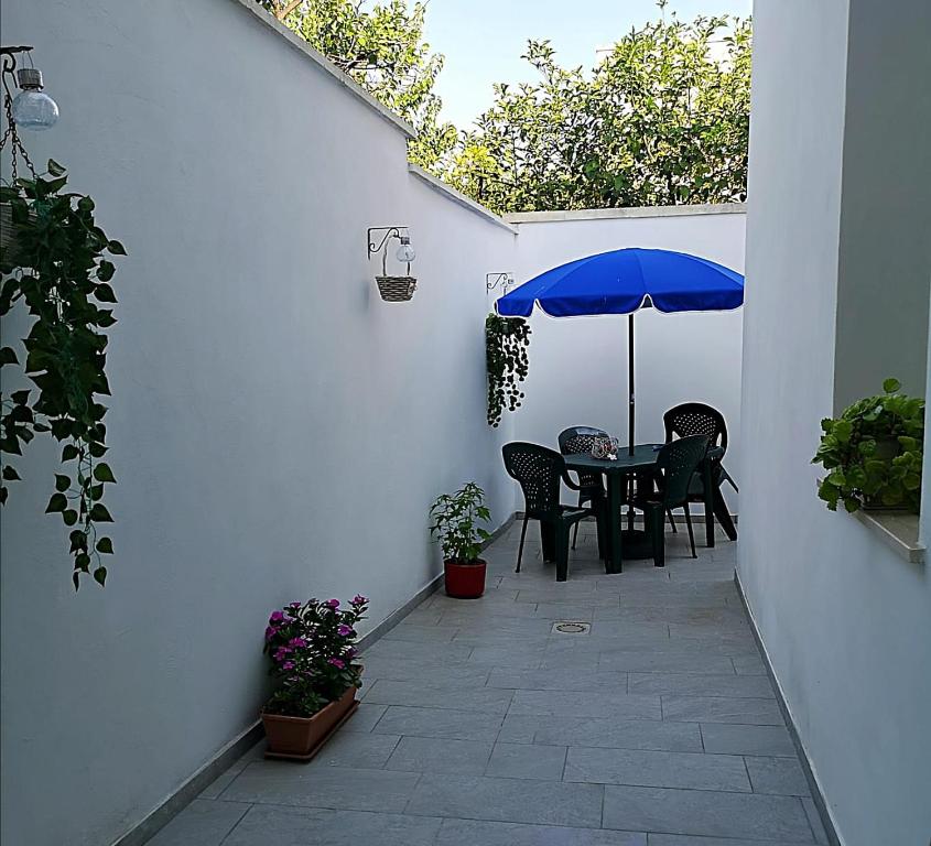 un patio con una mesa con una sombrilla azul en A Casa di Santé, en Arnesano