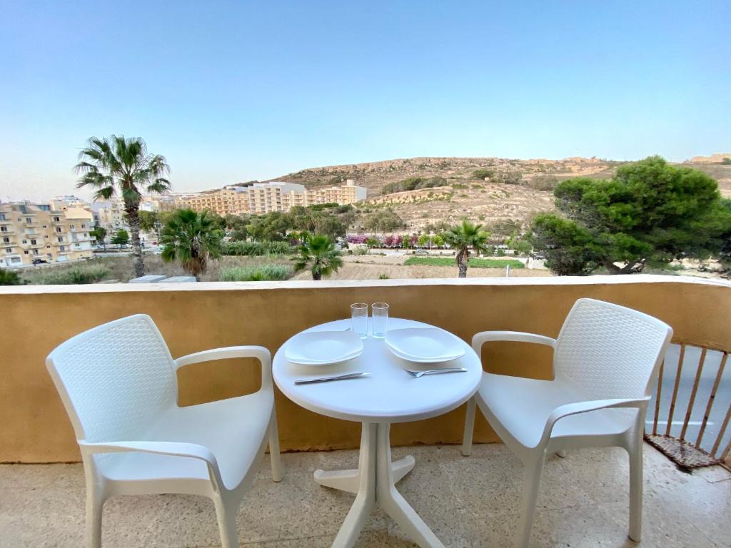 a white table and chairs on a balcony with a view at Gozo Belle Mare Apartments in Marsalforn