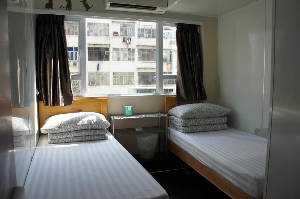 2 camas en una habitación pequeña con ventana en Ocean Inn, en Hong Kong