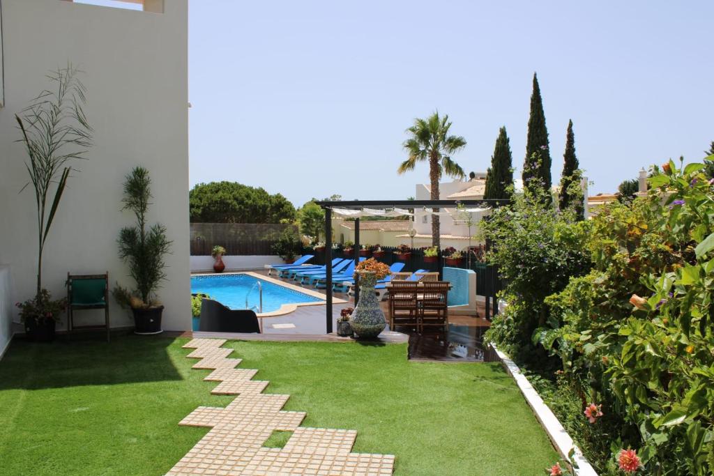 un patio trasero con piscina y césped verde en Villa Quinta do Algarve, en Albufeira