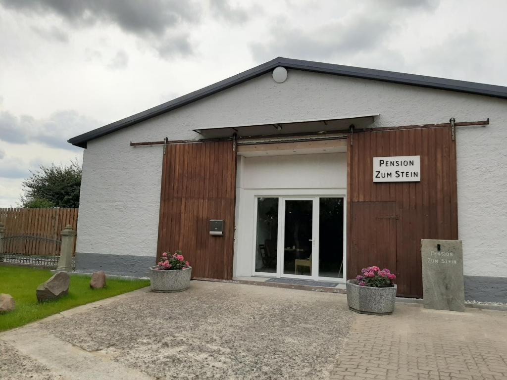 a white building with a sign on the door at Pension Zum Stein in Hohenkirchen