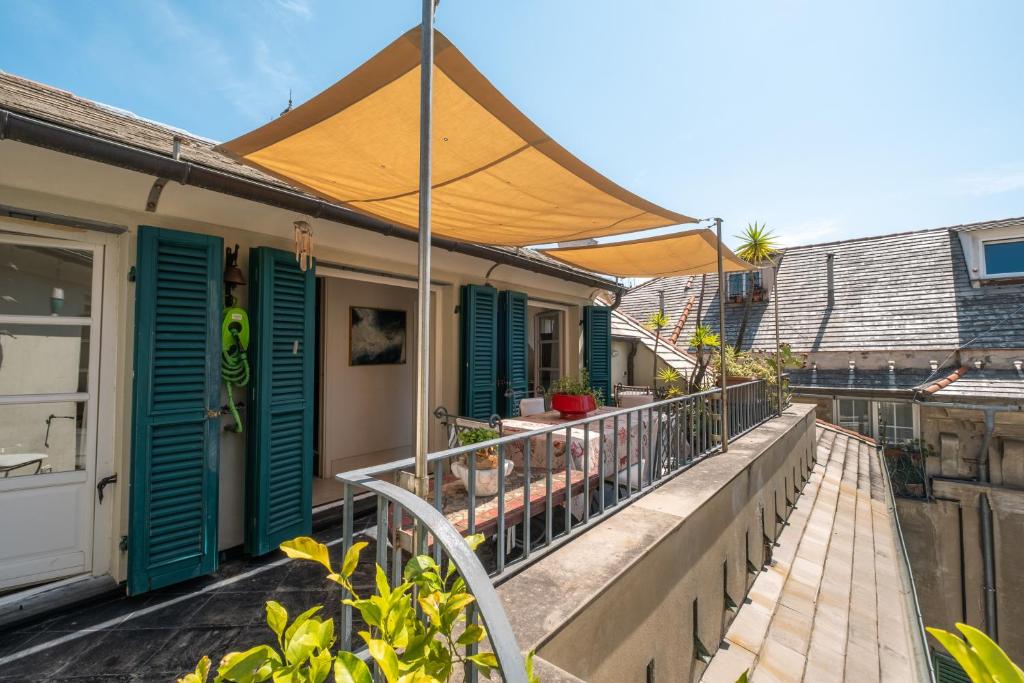 einen Balkon mit grünen Rollläden und einem Sonnenschirm in der Unterkunft Attico Palazzo Giustiniani in Genua