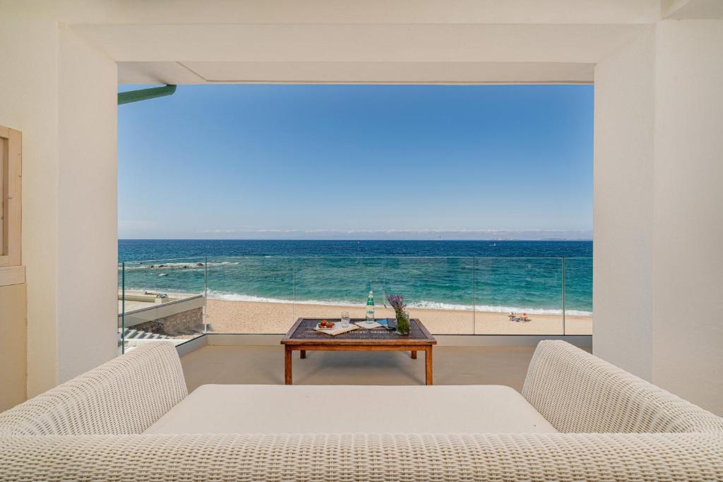 een woonkamer met een tafel en uitzicht op de oceaan bij Jatika Boutique Hotel in Aglientu