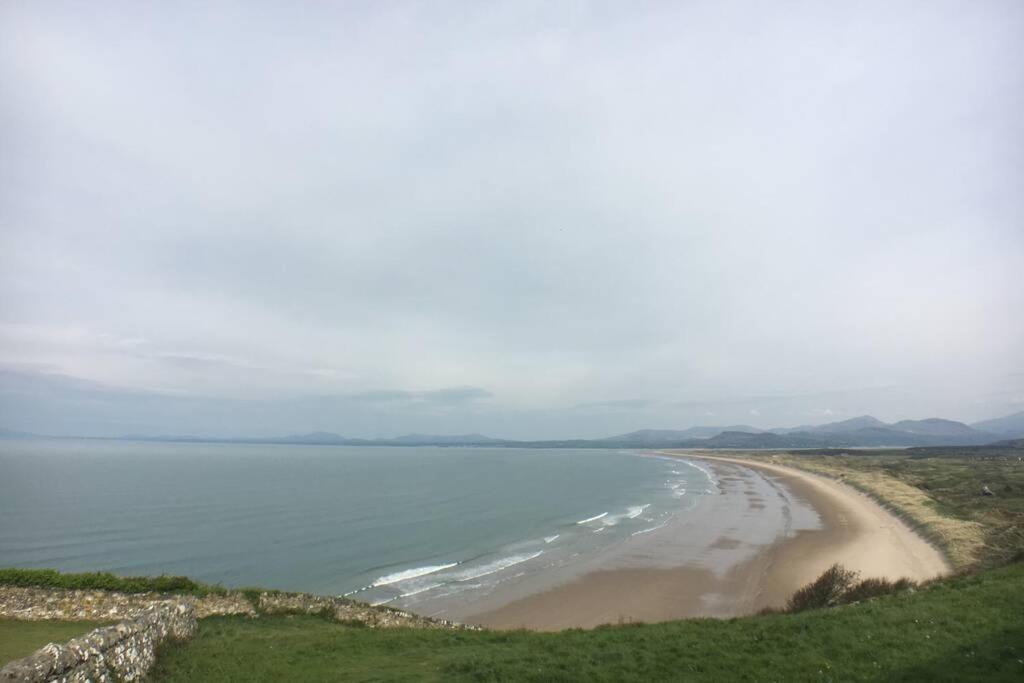 a view of a beach with the ocean in the background at Nyth Y Wiwer, Spacious and Peaceful Bungalow Near Harlech in Llanfair