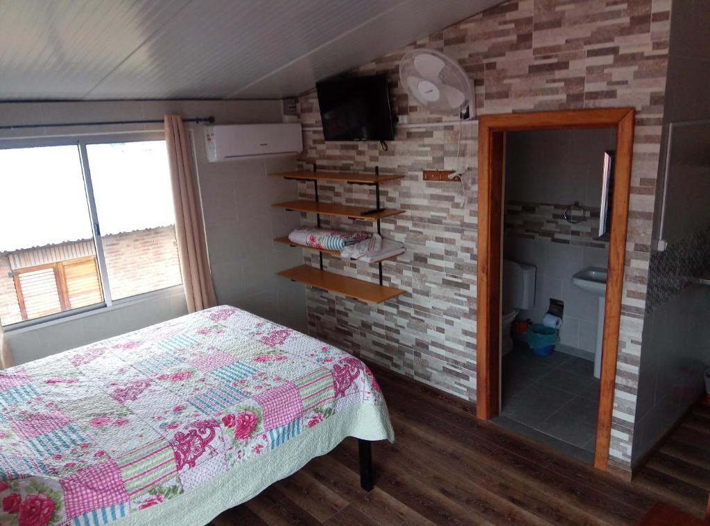 1 dormitorio con cama y pared de ladrillo en Habitación Dalian, en Termas de Guaviyú
