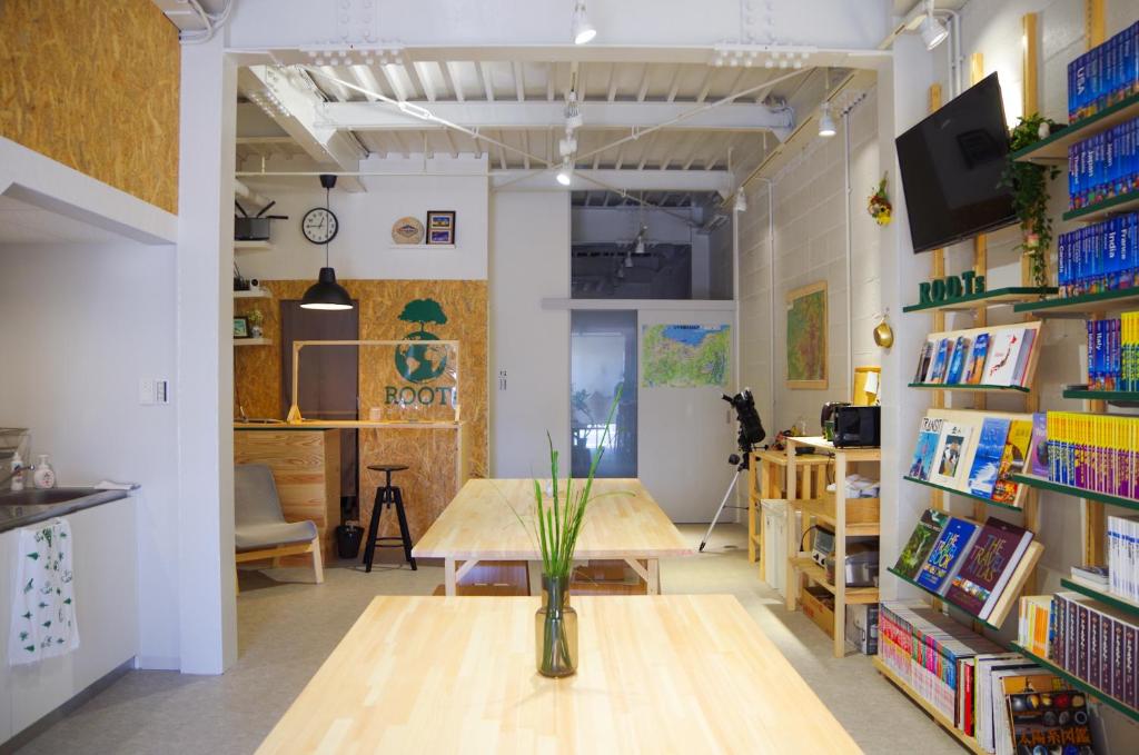 a room with a table and bookshelves at Travelers' house ROOTs in Takaoka