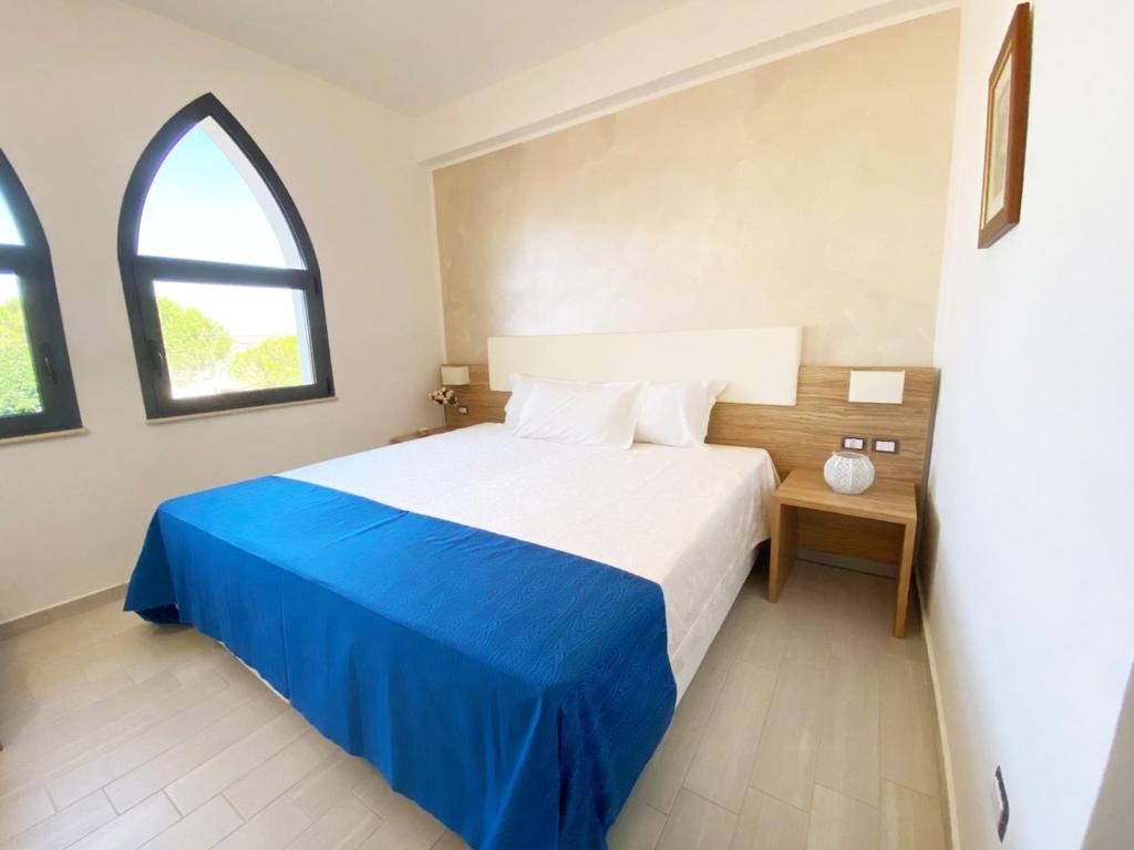 una camera con un letto blu e bianco e una finestra di La Rustica Hotel a Capo Rizzuto