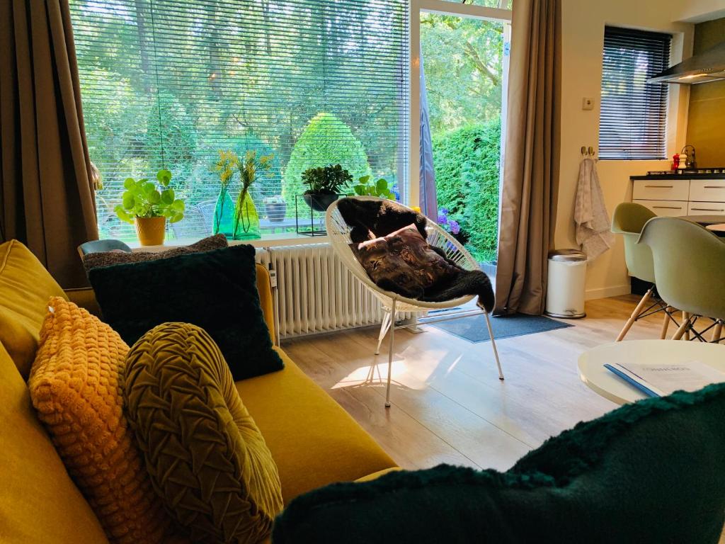 a living room with a yellow couch and a large window at Zonnebos, private garden, fresh air, relax! in Otterlo