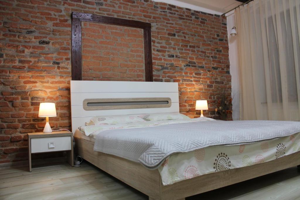 um quarto com uma cama e uma parede de tijolos em MSH Rustic apartment - Liars Bridge Sibiu em Sibiu