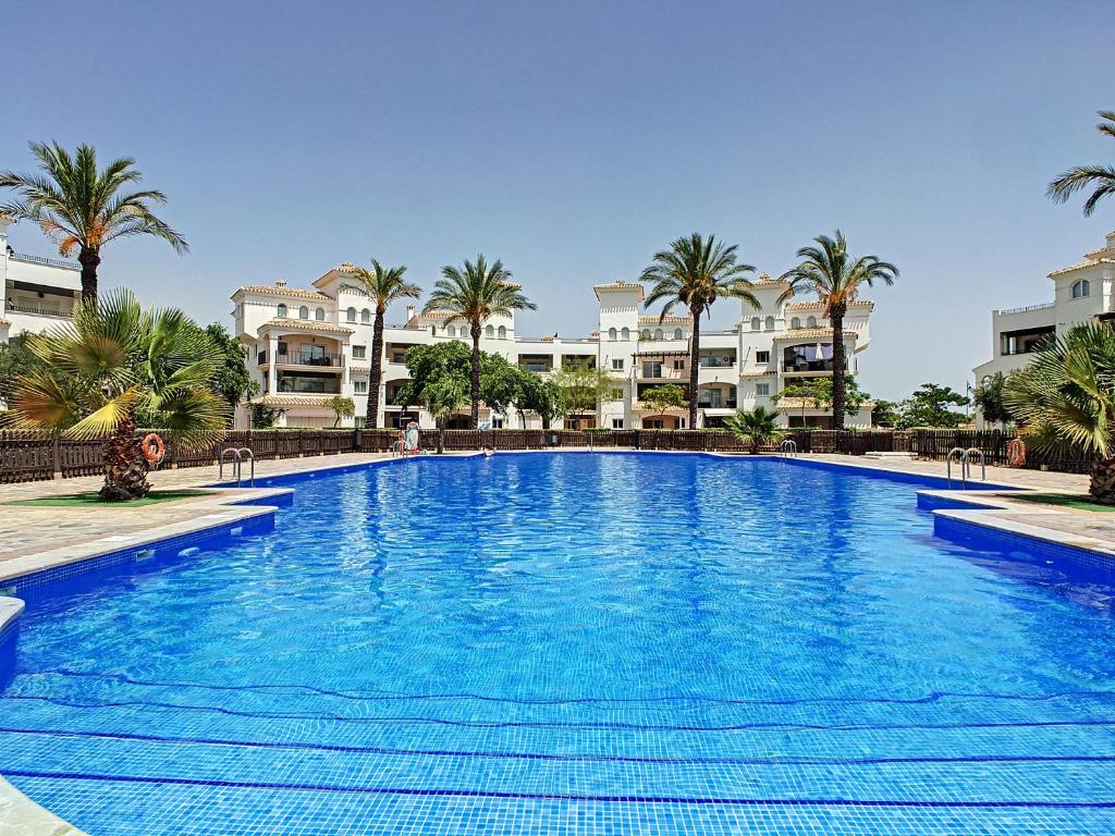 una gran piscina con palmeras y edificios en Hacienda Golf Resort - 8408, en Sucina