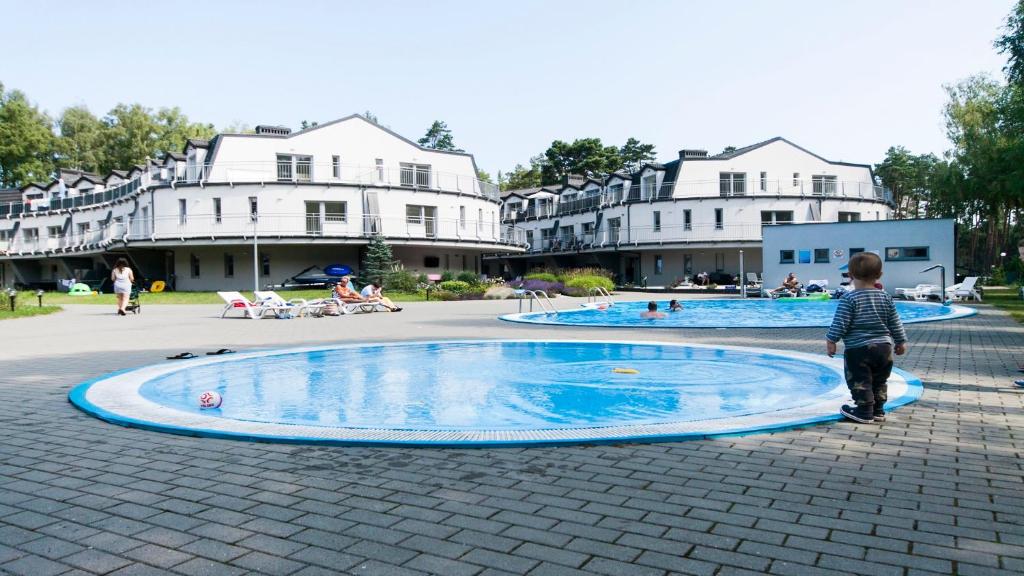 a young boy standing in front of a swimming pool at Lesna Dreams Apartament in Pobierowo