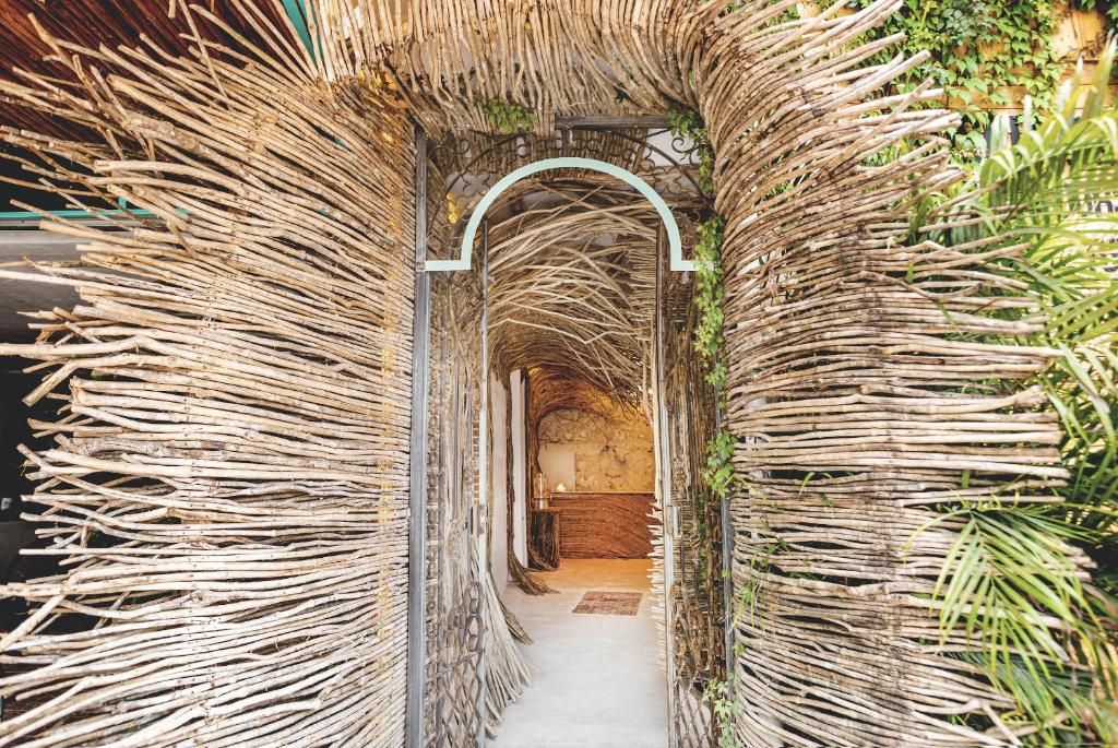 a wicker archway in a building with plants at LA TULUMEÑA Boutique Hotel in Tulum