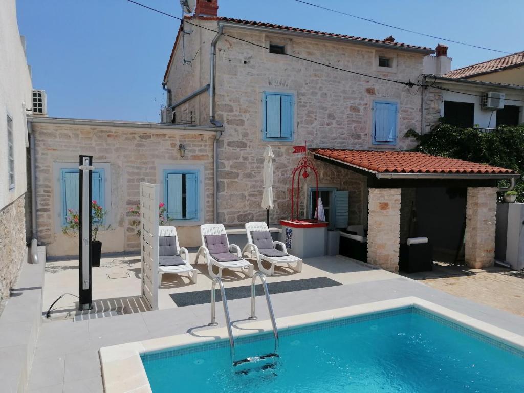 a house with a swimming pool and two lawn chairs at Holiday Home Peruski in Peruški