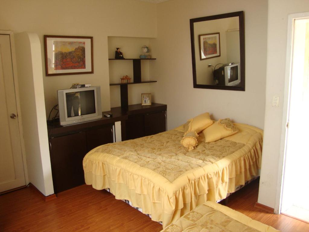 um quarto com uma cama e uma televisão em Petite Maison em Quito