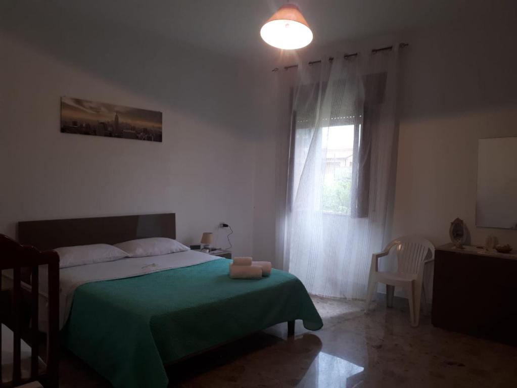 1 dormitorio con 1 cama con manta verde y ventana en Acquamarine, en Marina di Fuscaldo