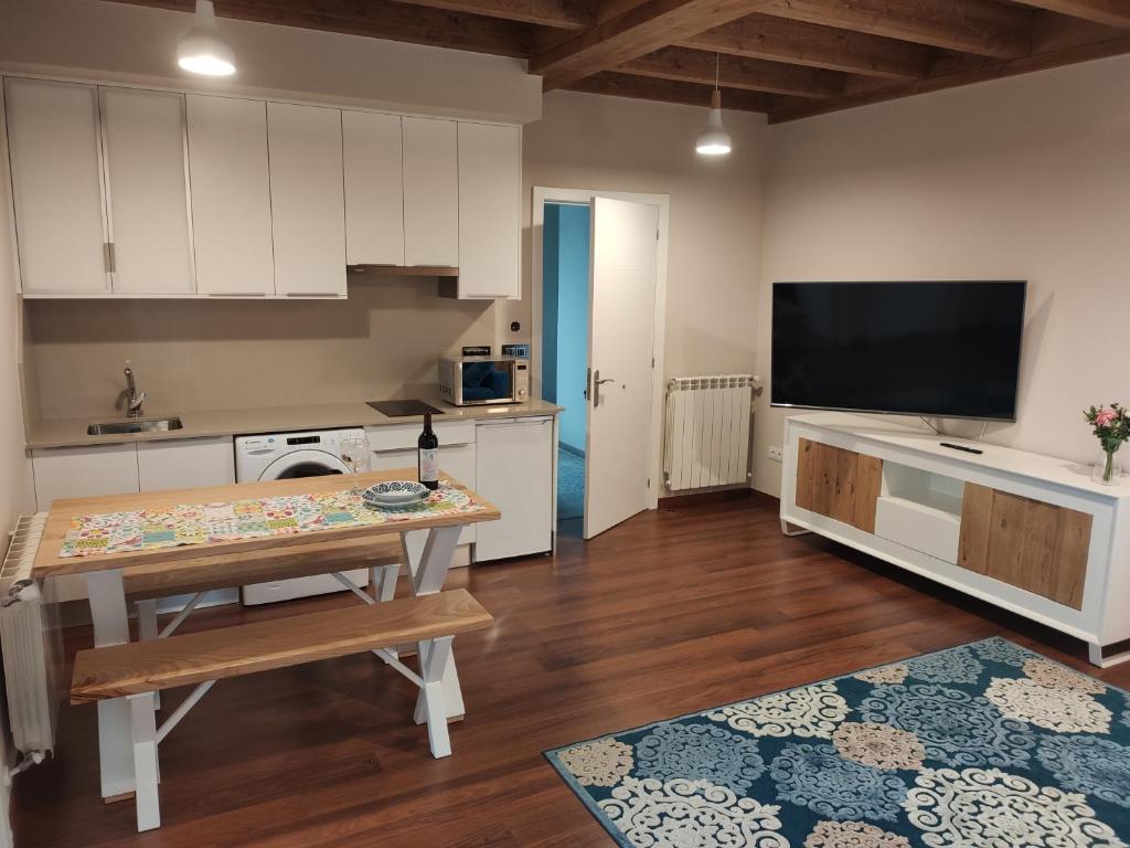 a kitchen with a table and a television in it at Apartamentos San Román in Retorta