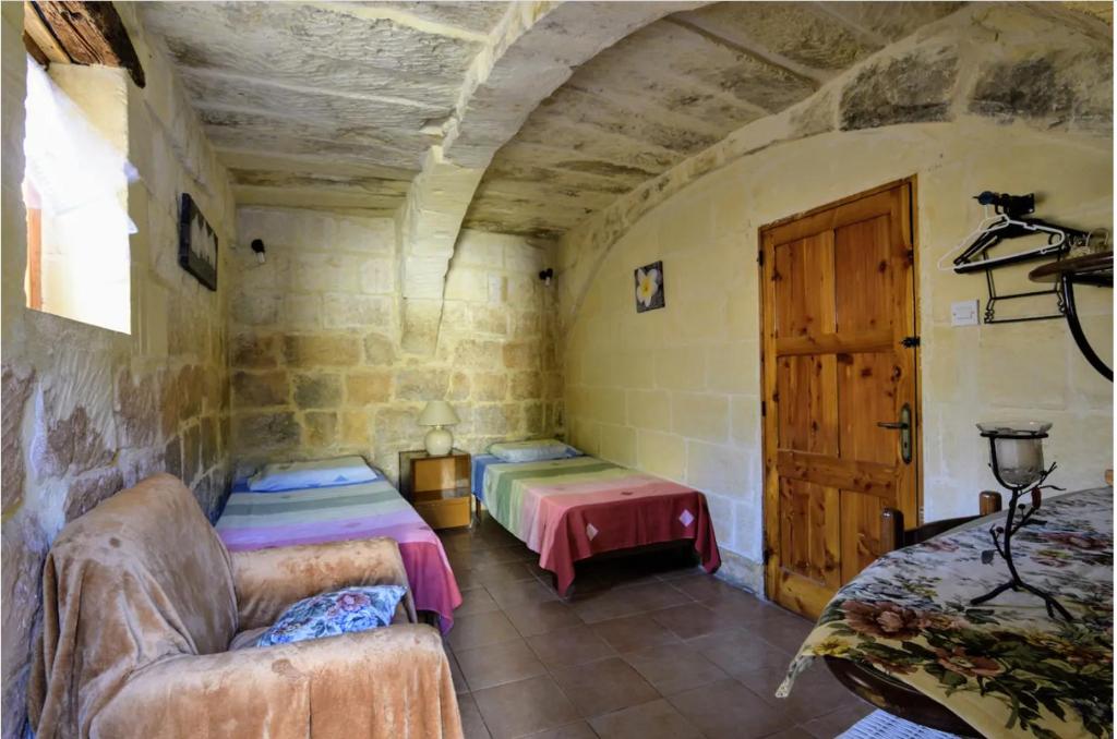 Habitación con 2 camas, sofá y puerta en 400YR Farmhouse in Xaghra Gozo - Separate Rooms, en Xagħra
