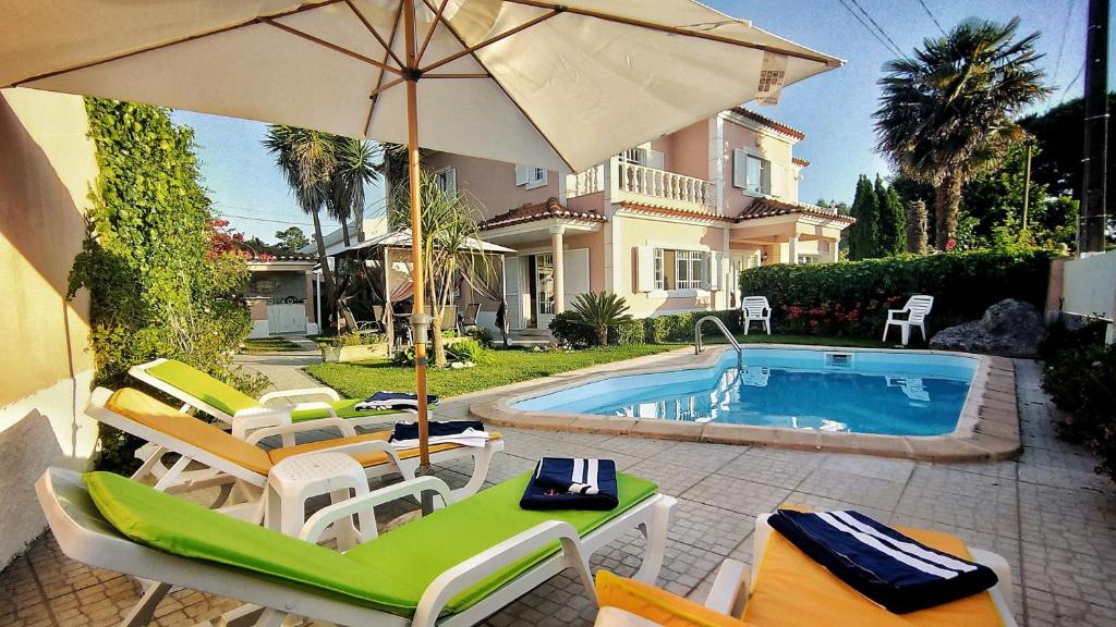 een patio met stoelen, een parasol en een zwembad bij Villa Shardana B&B in Sesimbra