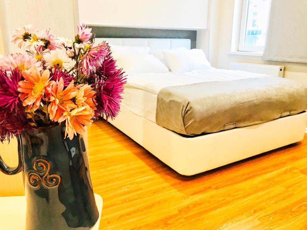 Eine Vase mit Blumen neben einem Bett in der Unterkunft Cozy Konka Apartments in Tbilisi City