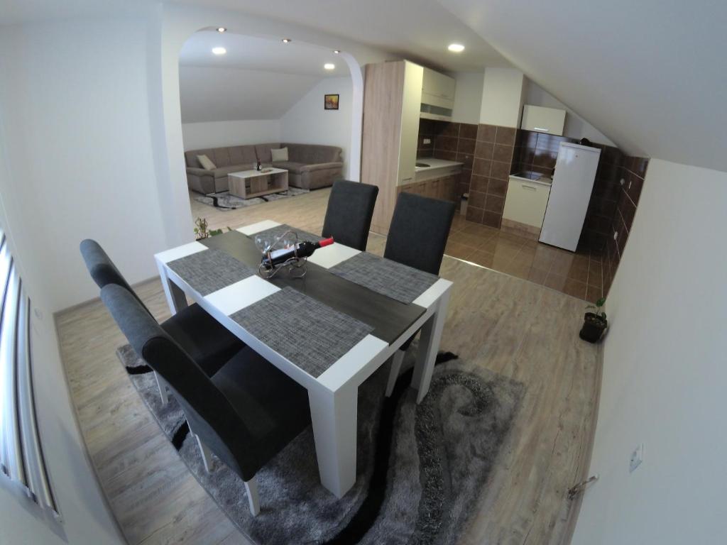 a dining room table with black chairs and a kitchen at Apartman Karganovic in Višegrad