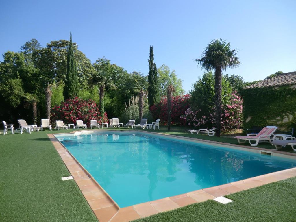 une grande piscine avec des chaises longues et des arbres dans l'établissement The Originals City, Hôtel du Parc, Avignon Est (Inter-Hotel), à Entraigues-sur-la-Sorgue