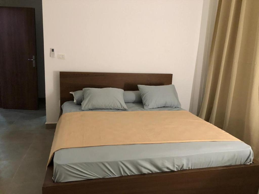 a bed with a wooden headboard and two pillows at Amwaj North Cosat in El Alamein