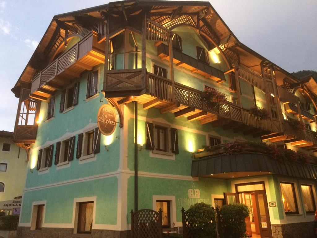 a building with a balcony on top of it at Hotel Alpina in Pinzolo