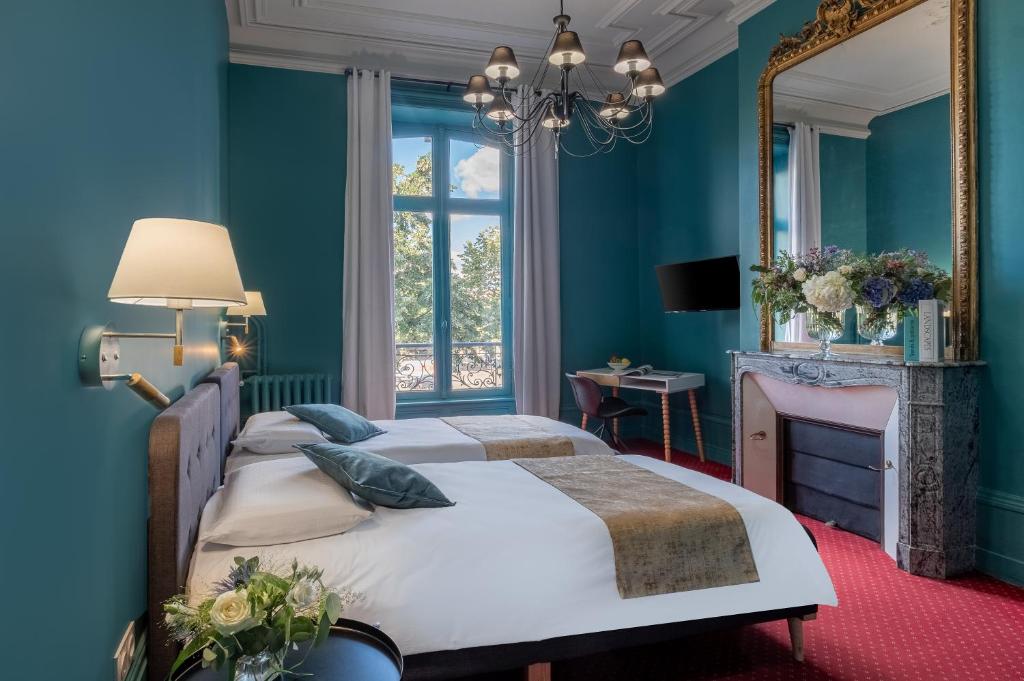 um quarto azul com 2 camas e um espelho em Hôtel de Paris em Limoges