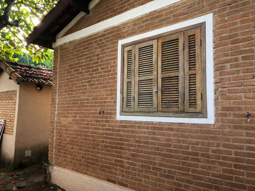 a brick building with a window with wooden shutters at Casinha de Campo bem localizada in Atibaia
