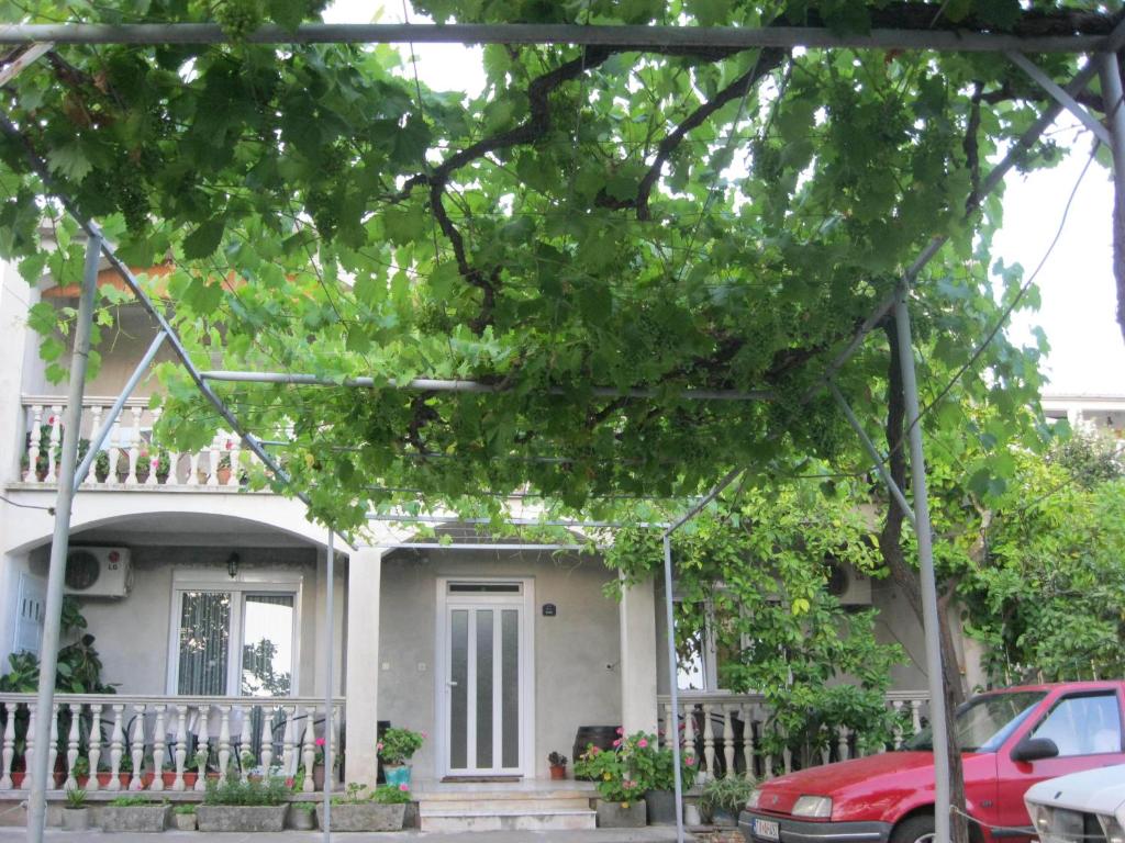 a white house with a red car parked in front of it at Apartments Miana in Tivat