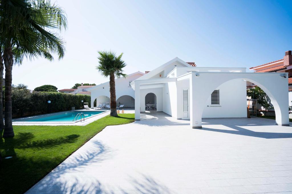 ein weißes Haus mit einem Pool und Palmen in der Unterkunft Le Agavi - Villa esclusiva per vacanze in Carini